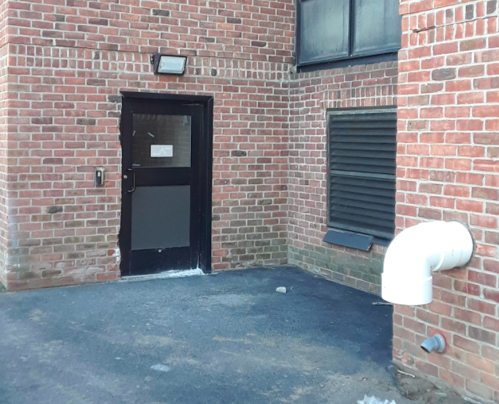 砖砌建筑后门，金属黑门，紧挨着天然气排热管 