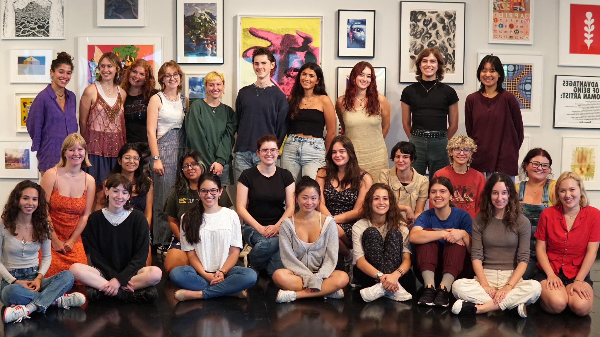 The Tang Student Advisory Council stand and sit against a backdrop of art in the Frances Young Tang Teaching Museum and Art Gallery.